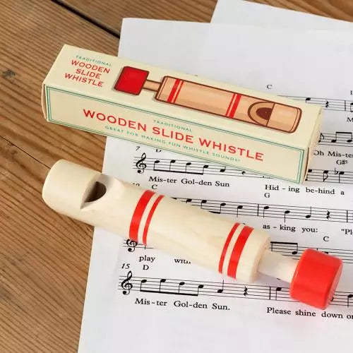 Traditional Wooden Slide Whistle and its packaging on top of sheet music. 