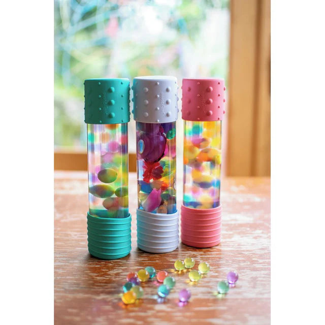 Three colorful tubes with beads on a wooden surface