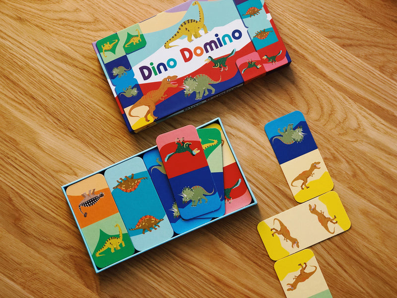 Dino Domino game set on a wooden surface with colorful dinosaur-themed cards.