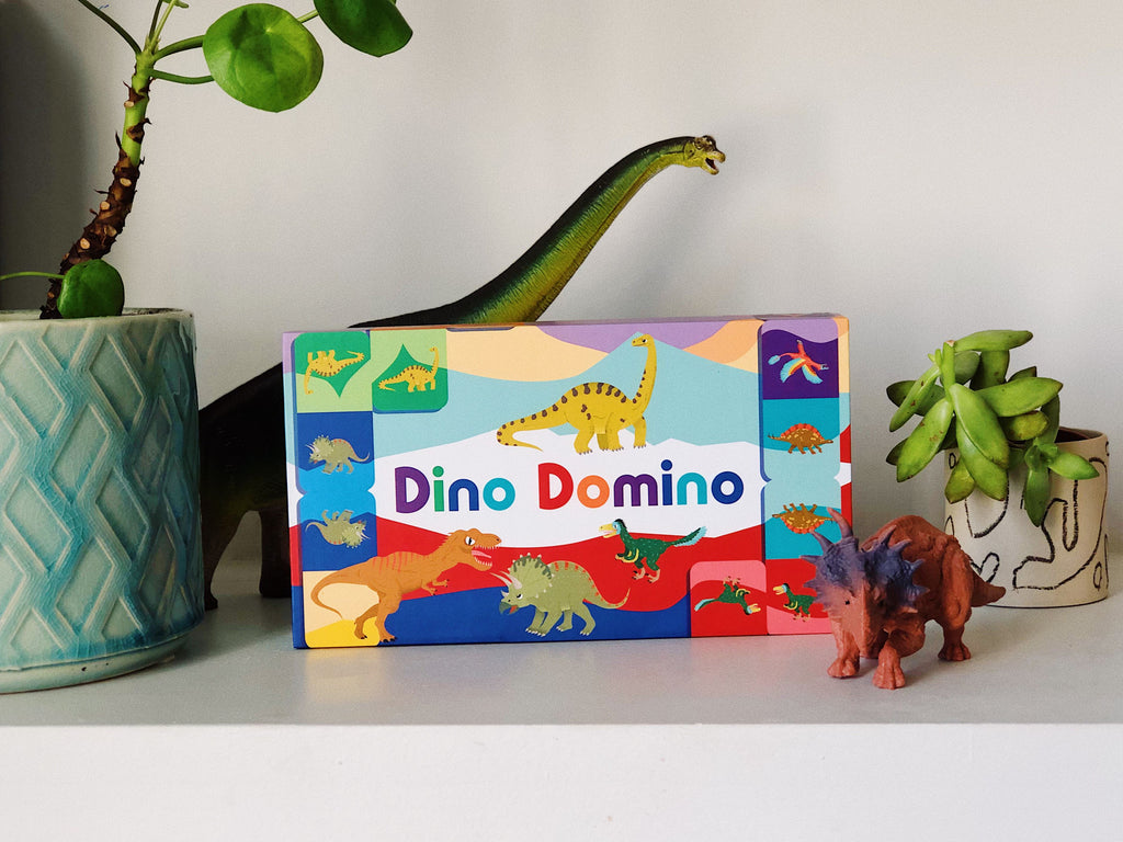 Dino Domino toy box with dinosaur figures on a white surface