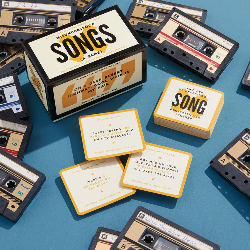 Board game box titled 'Songs' surrounded by cassette tape-themed cards on a blue background