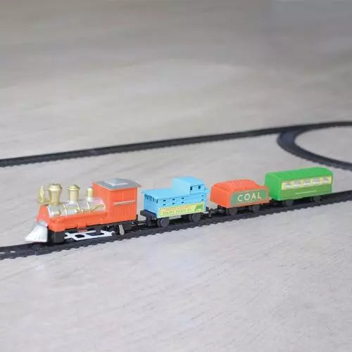 Traditional miniature train set, set out on a wooden floor. 
